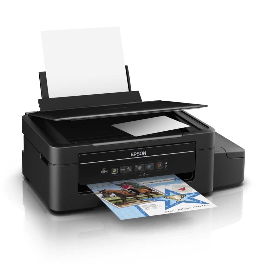 A black Epson all-in-one inkjet printer with a paper sheet loaded at the back and a colourful page being printed at the front. The printer’s scanner lid is slightly open, and control buttons are visible on the front panel.