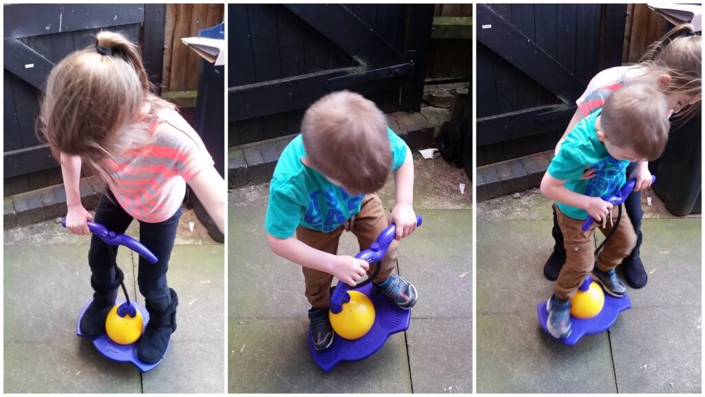 Three photos show two young children with light brown hair, playing outside on a purple and yellow balance toy. In each image, they balance and hold onto handles, taking turns or playing together on a paved patio, near a black wooden fence.