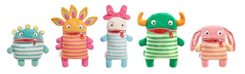 Five colourful plush monster toys stand in a row, each with a striped body, zip mouth, and unique shapes, colours, and features like horns, bows, petals, or bunny ears, all against a white background.
