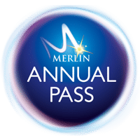 A circular logo with a glowing blue centre features the text “MERLIN” with a stylised “M” and a starburst, above the words “ANNUAL PASS” in white capital letters. The logo has a shiny, iridescent border.