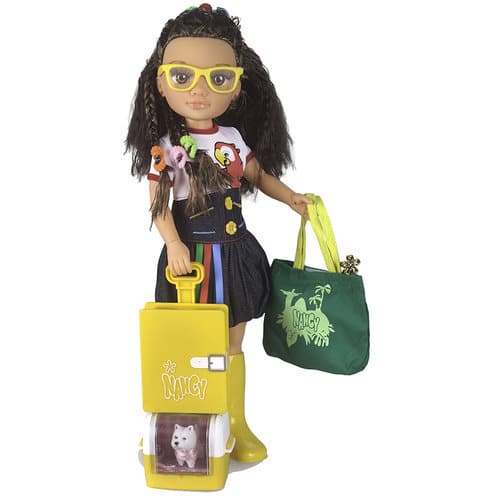 A fashion doll with long dark hair, yellow glasses, and a colourful outfit stands holding a green bag in one hand. She wears yellow boots and holds a yellow rolling suitcase with a clear pet carrier compartment, where a small white toy cat is visible inside.