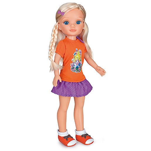 A blonde doll with blue eyes wears an orange T-shirt featuring Disney princesses, a purple polka-dot skirt, orange trainers with white socks, and a purple hair clip. One side of her hair is styled in a plait. The doll stands upright against a white background.