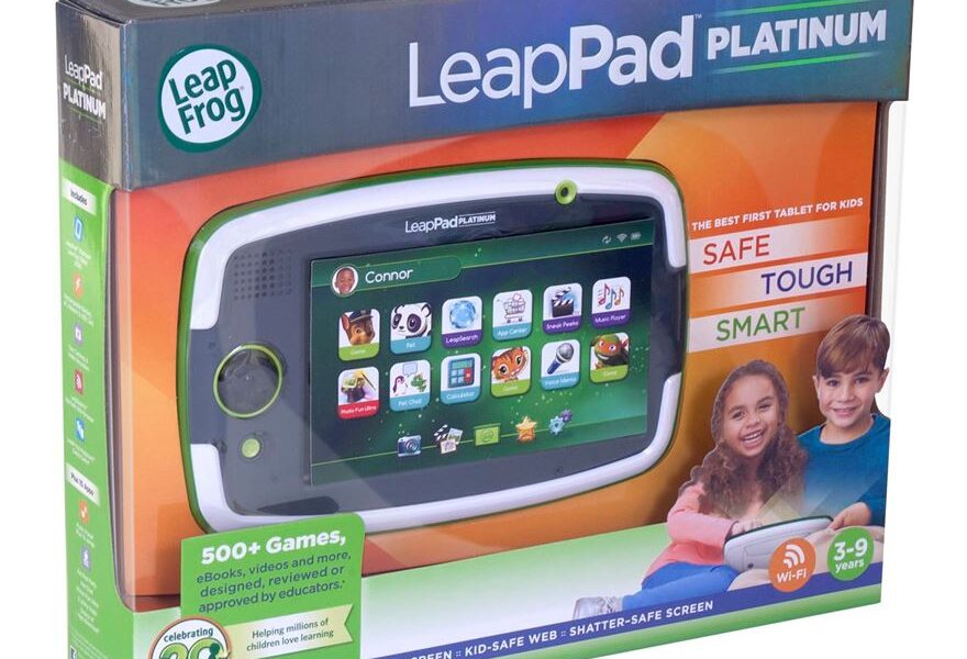 A LeapFrog LeapPad Platinum tablet in its box. The box is green and purple, showing the tablet screen with children’s apps. Text highlights features like "Safe," "Tough," "Smart," for ages 3–9, and advertises 500+ games, WiFi, and a 7-inch hi-res screen.