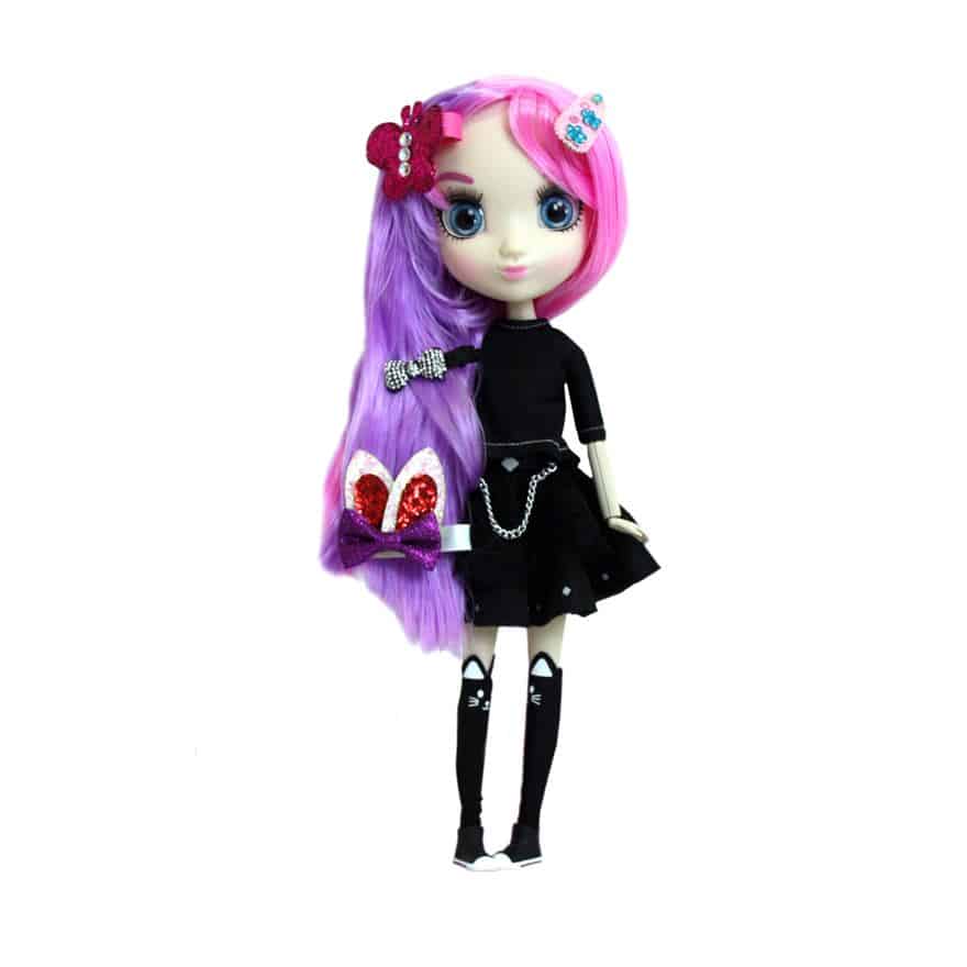 A fashion doll with large blue eyes, pink and purple long hair, and decorative hair clips. She wears a black crop top, black skirt with chains, and black knee-high socks with white bows. The background is plain white.