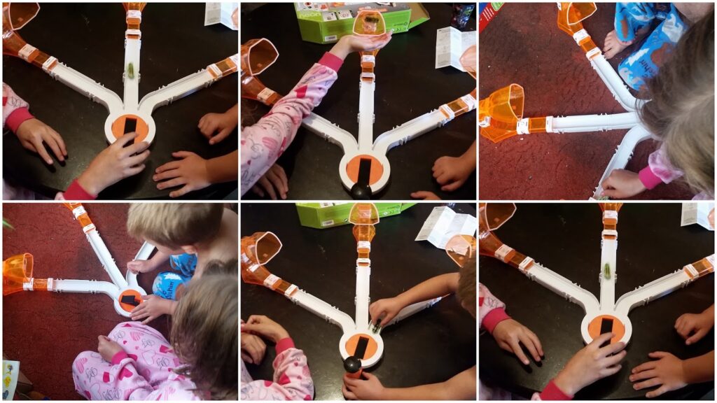 Six-panel collage showing children in pyjamas playing a tabletop game with white and orange plastic tracks radiating from a central hub. The children's hands interact with different parts of the game, moving objects along the tracks on a dark surface.