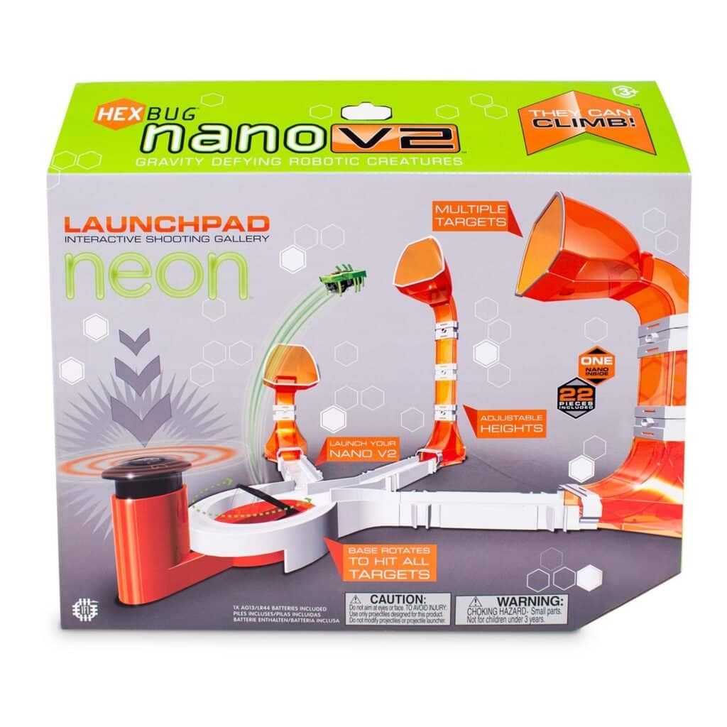 Box for the HEXBUG Nano V2 Launchpad toy. The packaging is green and white, showing the toy’s interactive shooting gallery with orange ramps, targets, and a Nano bug mid-air. Text highlights features like “multiple targets” and “adjustable heights”.