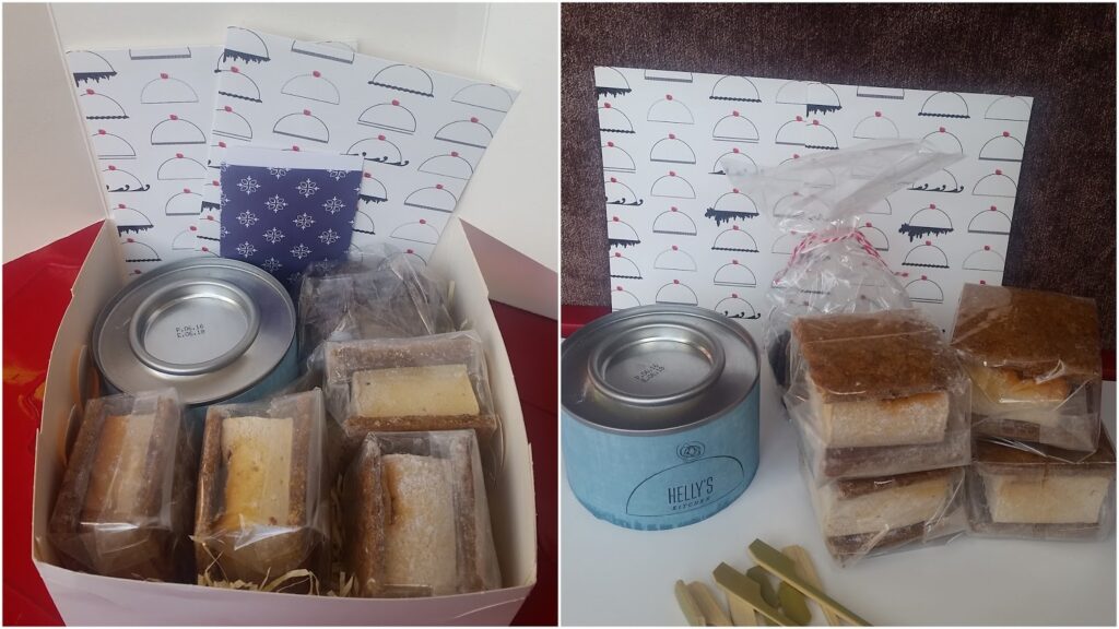 The image shows two boxes containing individually wrapped cake slices, a round tin, wooden forks, and cards with a cake dome pattern. The cakes are neatly packed, and the boxes have decorative paper or packaging, giving a gift-like presentation.
