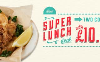 A plate with crispy fried seafood, leafy greens, a lemon wedge, and a small bowl of dipping sauce sits beside text advertising a “Super Lunch deal: two courses only £10.95” in bright, bold lettering.
