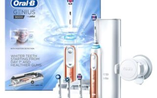Oral-B Genius 9000 electric toothbrush set with white and rose gold handle, four brush heads, a charging stand, a travel case, and a smartphone holder. The product packaging is shown in the background.