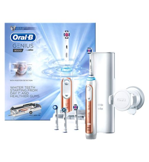 Oral-B Genius 9000 electric toothbrush set with white and rose gold handle, four brush heads, a charging stand, a travel case, and a smartphone holder. The product packaging is shown in the background.