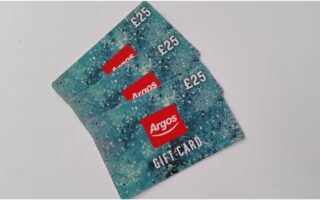 Three Argos gift cards, each valued at £25, are fanned out on a white surface. The cards have a speckled blue-green background and display the Argos logo in red, with the word "GIFT CARD" written in white underneath.