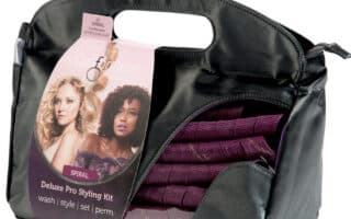 A black carrying case with a handle, containing a purple Curlformers Deluxe Pro Styling Kit. The packaging shows two women with curly hair and includes text: “Deluxe Pro Styling Kit—wash | style | set | perm.” The spiral curlers are visible inside the case.