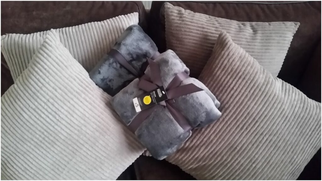 A blanket wrapped in a ribbon on a sofa.