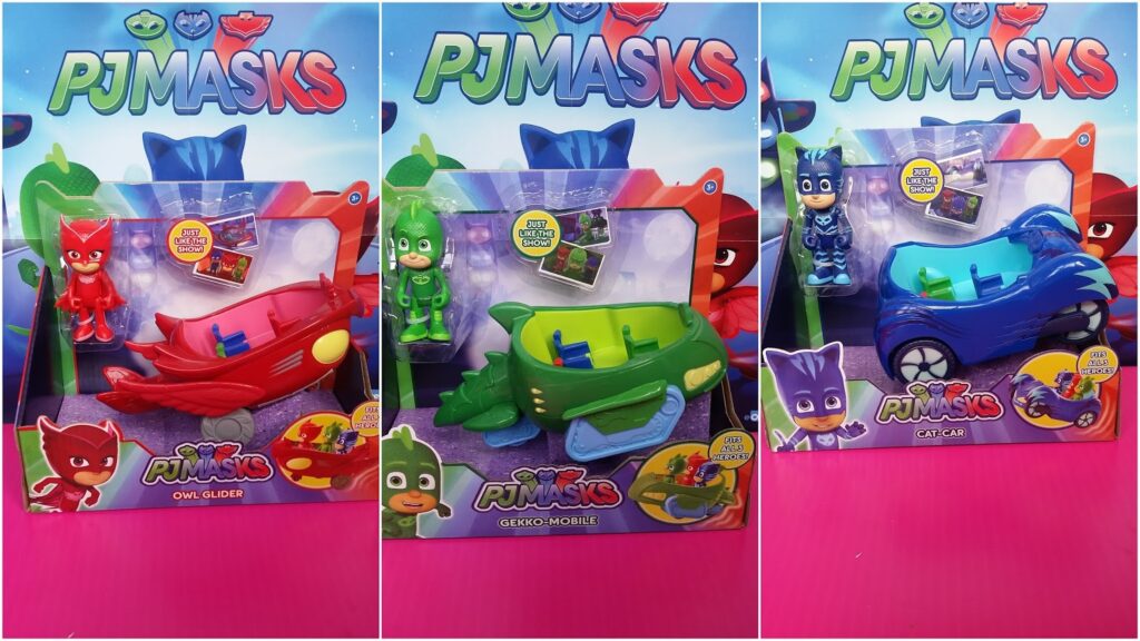Three PJ Masks toy sets on display. Each set includes a character figure (Owlette, Gekko, or Catboy) and their matching vehicle (red Owl Glider, green Gekko-Mobile, or blue Cat-Car) in colourful packaging with PJ Masks branding on a pink background.