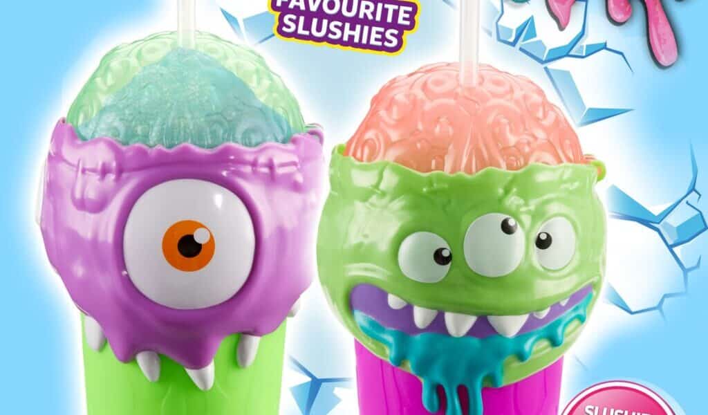 Two colourful slushy cups shaped like monster faces—one purple with one eye, the other green with two eyes and blue drool—sit on an icy blue background. Text reads: "Frozen Brain Slushy Maker," "Prepare your favourite slushies," and "Freeze, Squeeze and Enjoy!".
