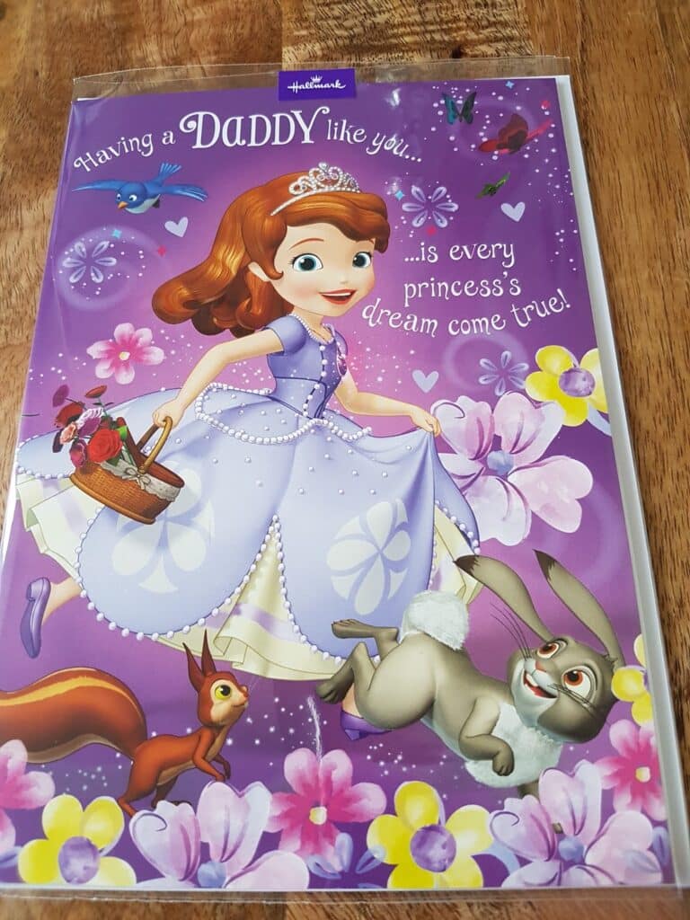 A greeting card features Princess Sofia in a lavender dress holding a basket of flowers, surrounded by colourful flowers, a squirrel, and a rabbit on a purple background. The text reads, "Having a daddy like you... is every princess's dream come true!".