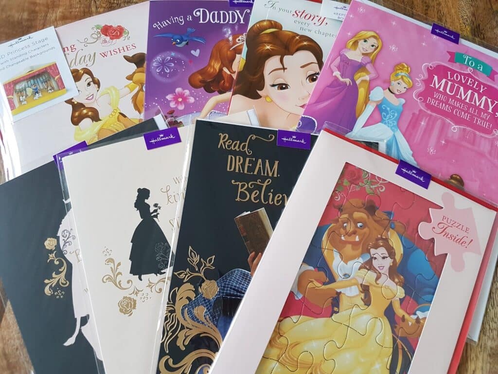 A collection of Disney-themed Hallmark cards and a puzzle, featuring princesses like Belle from Beauty and the Beast, and other characters. The cards have colourful illustrations, gold accents, and messages for mums, dads, and birthdays.