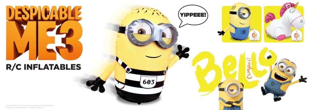 Image features a large "Despicable Me 3 R/C Inflatables" title on the left. Centre is a remote-control inflatable Minion in a black-and-white prison suit with arms out and saying "YIPPEEE!". Right side shows another Minion, a fluffy unicorn, and "Bello" text.