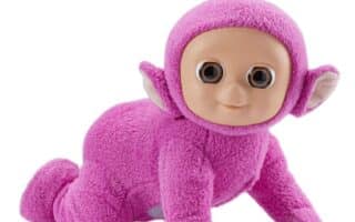 A cuddly toy resembling a cartoonish humanoid creature with bright pink fuzzy fabric, large round brown eyes, pointy ears, a tan plastic face, and a small round aerial on its head, posed crawling on all fours against a white background.