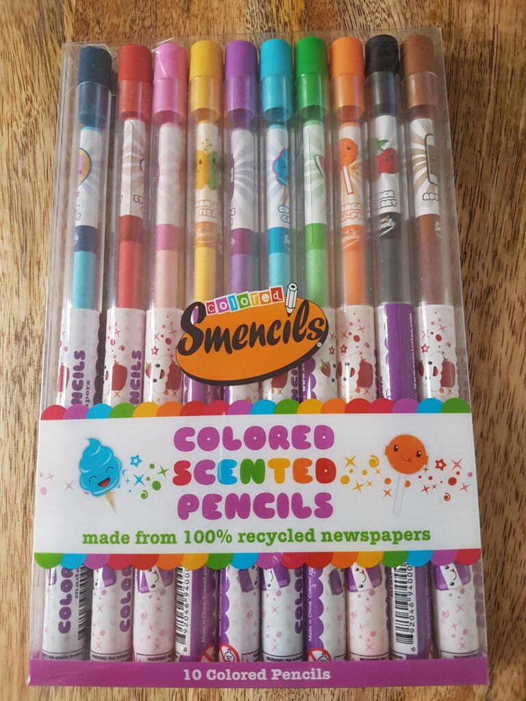 A pack of 10 Smencils coloured scented pencils in a clear plastic case. Each pencil has a different colour and cartoon character design, with text reading “Coloured Scented Pencils” and “made from 100% recycled newspapers” on the front label.