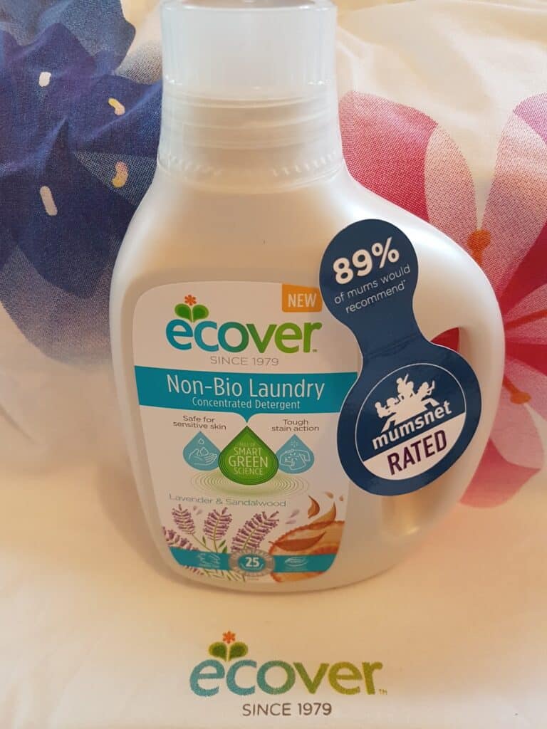 A bottle of Ecover Non-Bio Laundry Concentrated Detergent with lavender and sandalwood scent sits on a fabric with floral patterns. The label highlights 89% of mums would recommend it and displays a “Mumsnet Rated” badge.