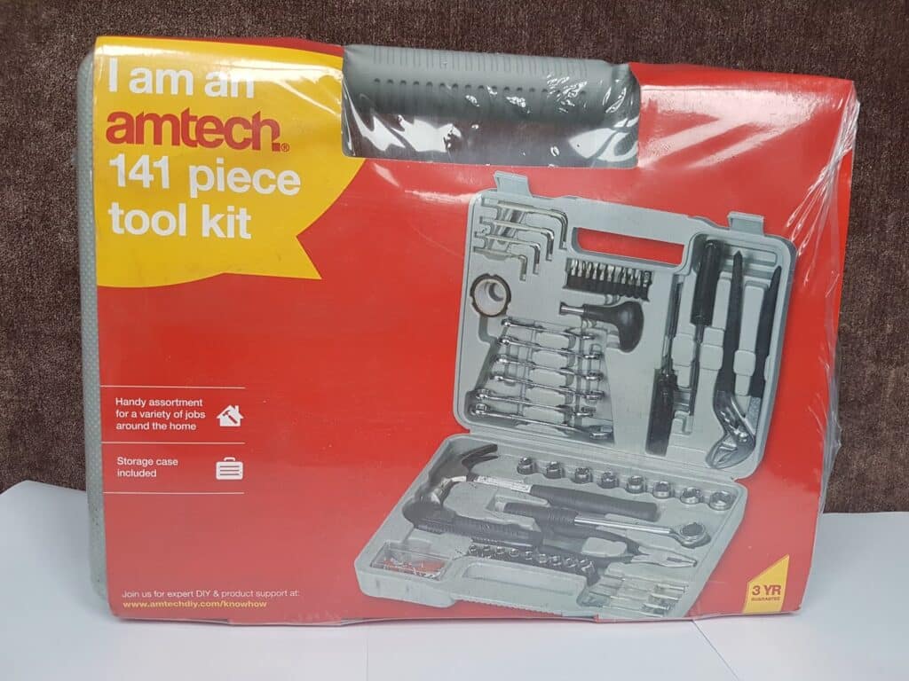 A red and grey box labelled "I am an amtech 141 piece tool kit" displays images of a tool set inside a grey plastic case. The box highlights features like a "Handy assortment," "Storage case included," and shows various hand tools neatly arranged.