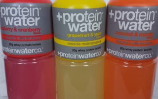 Three bottles of +Protein Water are side by side. Flavours are raspberry & cranberry (pink), grapefruit & yuzu (yellow), and coconut & mango (orange). Each label highlights "muscle maintenance" and "20g whey protein isolate.