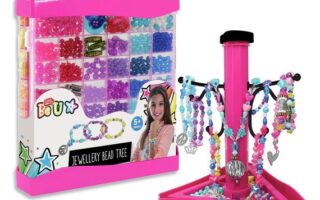 A pink jewellery bead kit box with compartments filled with colourful beads, charms, and string, alongside a pink jewellery tree stand displaying completed bracelets and necklaces in various colours and styles. For ages 5 and up.