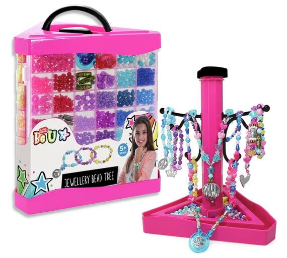 A pink jewellery bead kit box with compartments filled with colourful beads, charms, and string, alongside a pink jewellery tree stand displaying completed bracelets and necklaces in various colours and styles. For ages 5 and up.
