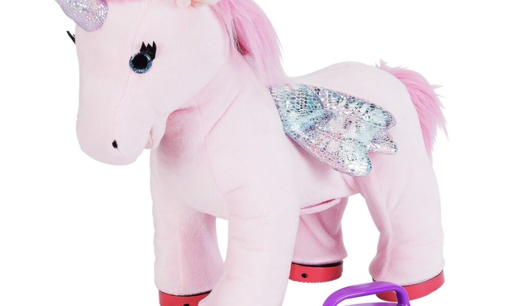 A large, soft pink unicorn plush toy with sparkly silver wings, a shimmering horn, pink mane and tail, and red hooves. In front of it are a purple-handled brush and two toy cupcakes with pink icing. The background is white.