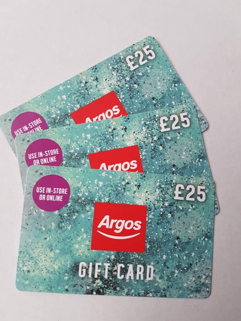 Three Argos £25 gift cards are stacked diagonally on a white background. The cards have a teal, speckled design with white dots, red Argos logos, and a purple circle stating “USE IN-STORE OR ONLINE”.