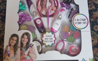 A boxed “Be U” Hair Beader & Braider Set for ages 5+, showing pink and white hair styling tools, colourful hair beads, combs, elastics, and accessories. The packaging features two smiling girls and text: “Create your own hairstyles” and “3-in-1 hair styler set.”.