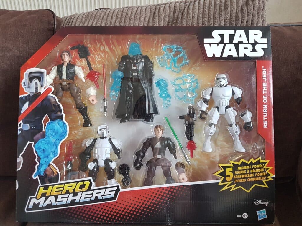 A boxed Star Wars “Hero Mashers: Return of the Jedi” toy set containing five mix-and-match action figures: Han Solo, Darth Vader, Stormtrooper, Biker Scout, and Luke Skywalker, with extra accessories and interchangeable parts, displayed on a brown sofa.