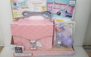 A Project Mc² Ultimate Spy Bag toy set is displayed in its packaging. The set includes a pink quilted bag with a silver lock and handle, and spy-themed tools. The packaging is colourful, showing accessories and instructions for children aged 6 and up.