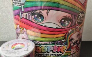Two colourful containers of Poopsie toys are shown. The large one features a unicorn with rainbow hair and big blue eyes. The smaller container shows a unicorn character holding glittery slime. Both packages are decorated with rainbows, stars, and playful text.