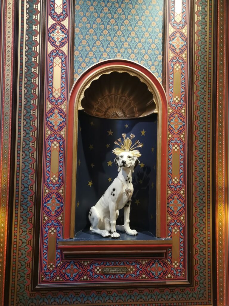 A porcelain Dalmatian with a golden starburst crown sits in a decorative alcove. The background is blue with gold stars, and the alcove is framed by ornate red and gold patterned panels, evoking a luxurious, regal atmosphere.