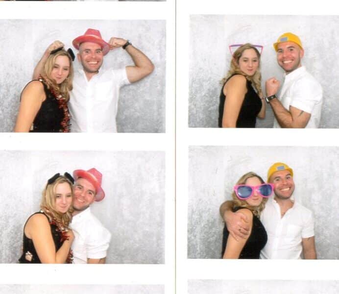 A photo booth strip features a smiling man and woman wearing fun hats and large pink glasses, posing playfully together against a light grey backdrop in various poses, including side-by-side, back-to-back, and with arms round each other.