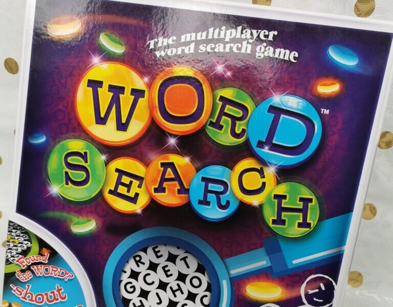 A board game box titled “Word Search” features colourful, bubble-like letters on a purple background with glowing circles. The tagline reads “The multiplayer word search game.” Icons at the bottom indicate recommended age and number of players.