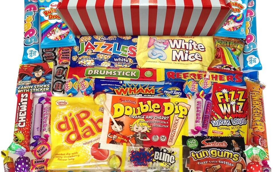 A red and white striped box sits open, overflowing with assorted colourful retro sweets, including Wham bars, Refresher chews, Dip Dab, Drumstick, Fizz Wiz, White Mice, Fun Gums, candy sticks, lollipops, and other treats, all neatly arranged in front.
