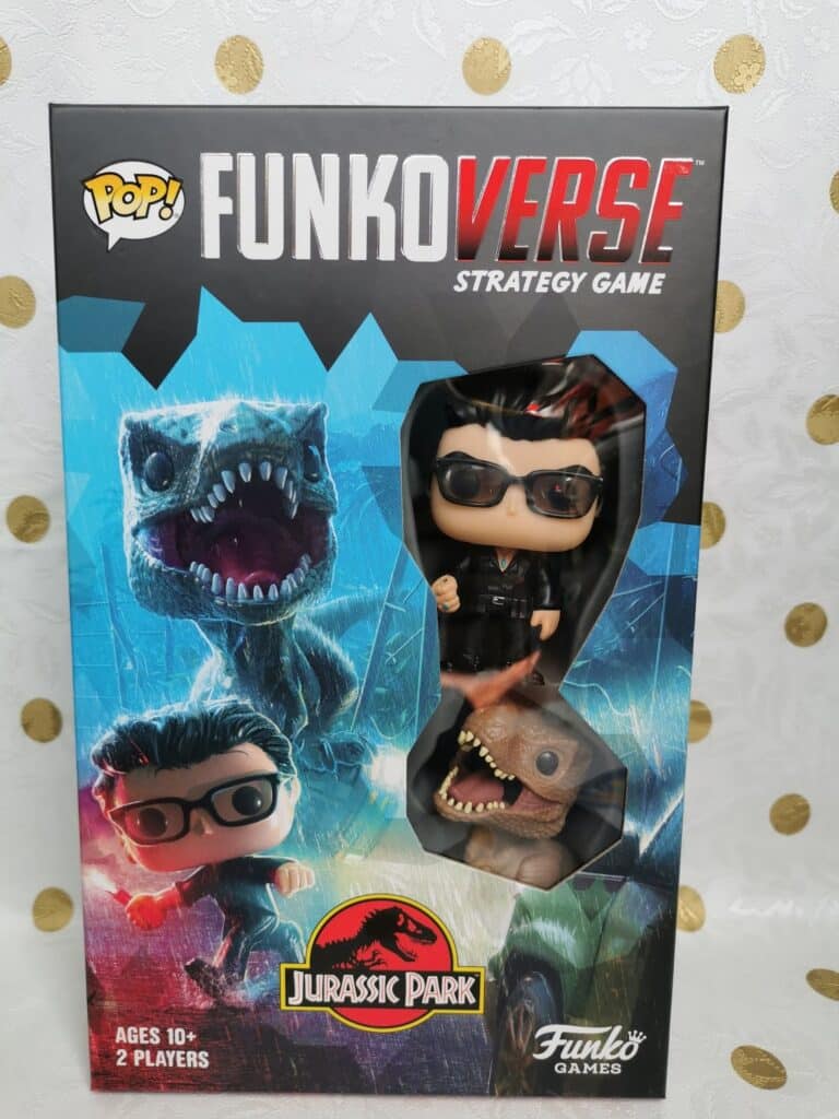The image shows the front of a "Funkoverse Strategy Game" box featuring Jurassic Park. The box displays Funko Pop! figures of Dr Ian Malcolm and a velociraptor, with Jurassic Park branding and game details for ages 10+ and 2 players.