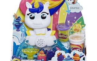 Play-Doh Tootie the Unicorn playset in colourful packaging. Tootie has a rainbow mane, large eyes, and a cheerful expression. Included are three Play-Doh pots and accessories. The background shows rainbows, stars, and Play-Doh creations. For ages 3 and over.