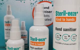 Three sizes of Steril-eeze+ "Kind to hands" hand sanitiser bottles are displayed in front of their packaging. The labels, mainly white and teal with orange highlights, indicate the product is alcohol-free and claims to kill 99.99% of viruses and bacteria.