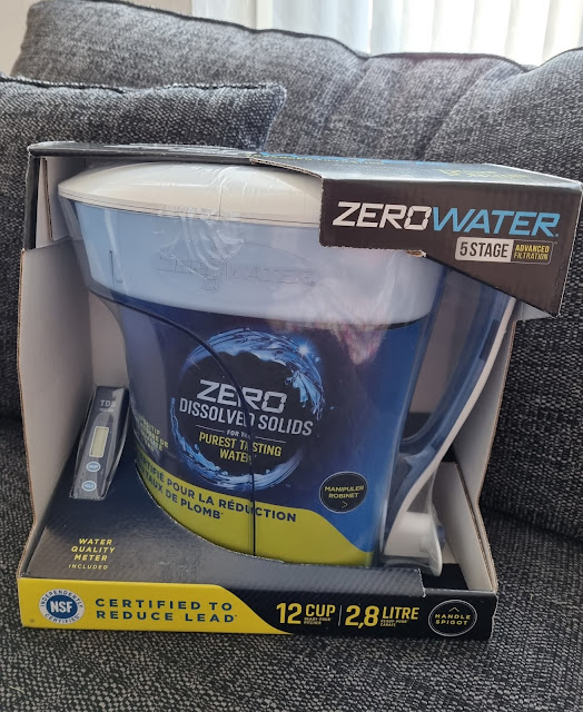A ZeroWater 12-cup water filter jug is shown in its box, featuring 5-stage advanced filtration. The packaging highlights “Zero Dissolved Solids,” includes a total dissolved solids meter, and mentions certification to reduce lead. The jug is blue and white.