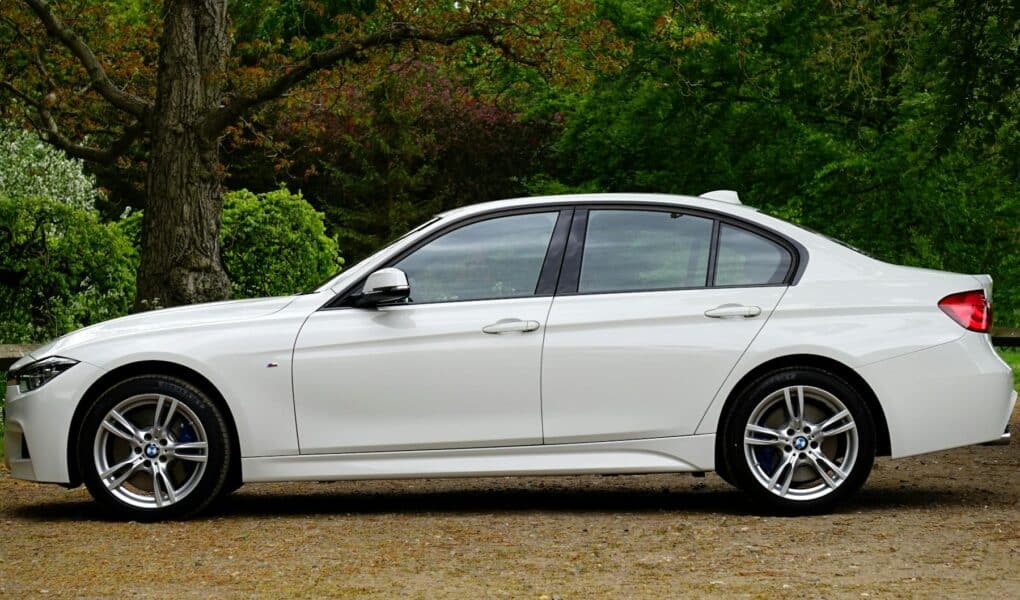 white bmw sedan parked beside tree