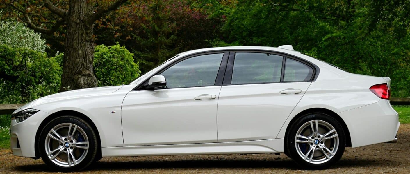 white bmw sedan parked beside tree