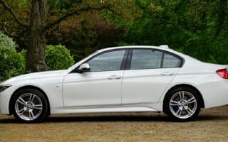 white bmw sedan parked beside tree