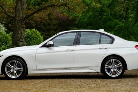 white bmw sedan parked beside tree