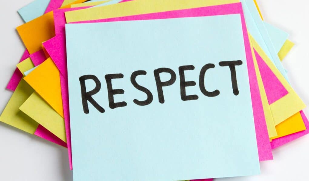 A stack of colourful sticky notes, with a blue note on top displaying the word "RESPECT" written in bold, black letters. The notes beneath are pink, yellow, and orange, creating a vibrant and positive background.