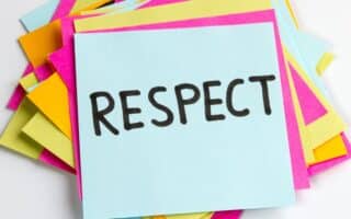 A stack of colourful sticky notes, with a blue note on top displaying the word "RESPECT" written in bold, black letters. The notes beneath are pink, yellow, and orange, creating a vibrant and positive background.