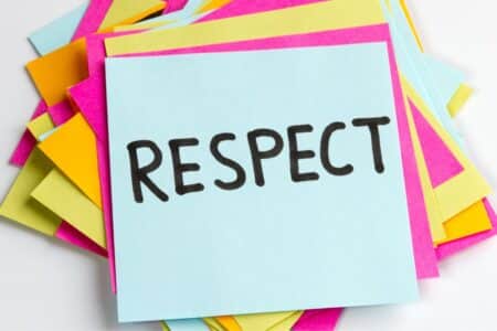 A stack of colourful sticky notes, with a blue note on top displaying the word "RESPECT" written in bold, black letters. The notes beneath are pink, yellow, and orange, creating a vibrant and positive background.